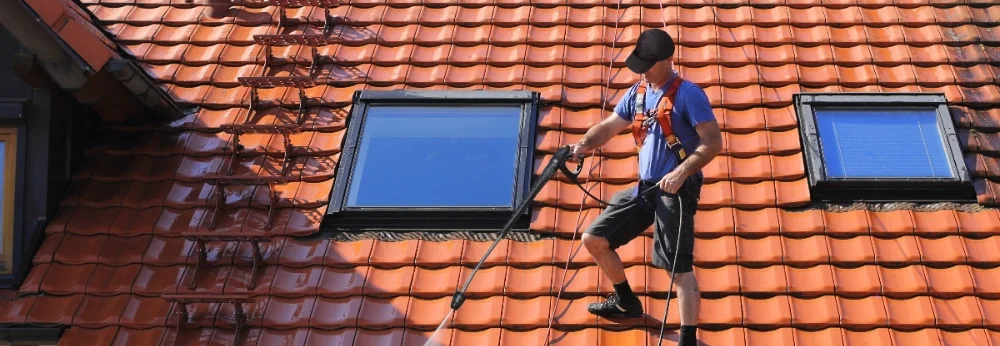 Person reinigt Dach mit Hochdruckreiniger